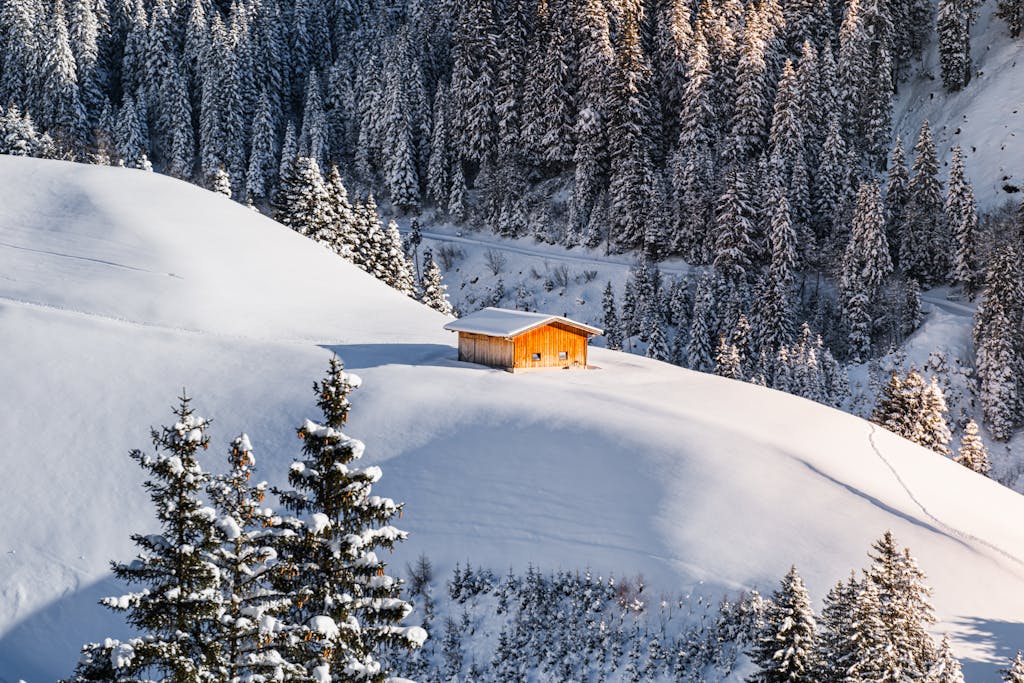 A cozy wooden cabin surrounded by snow-covered Alps in Zillertal, Austria.