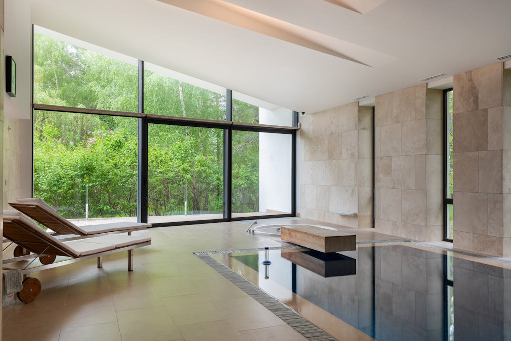Interior of contemporary large apartment with deck chairs and swimming pool with clean water in daytime