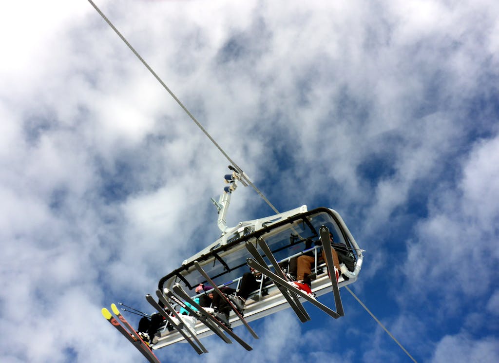 Skiers on a chairlift ride against a backdrop of clouds in Kaprun, Austria.