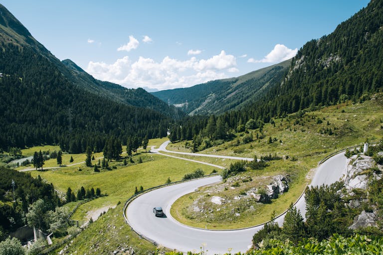 A captivating scenic view of a winding road through the lush green mountains and valleys of Tyrol, Austria.
